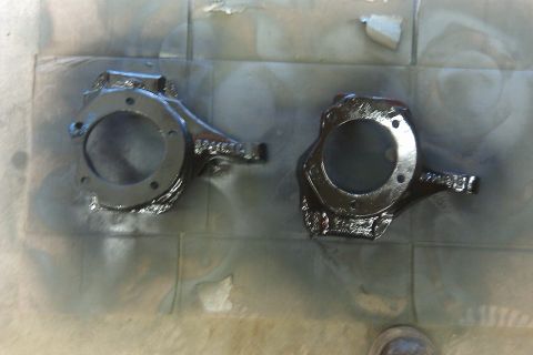 1993 Ford F-150 - Two freshly painted steering knuckles are laid out on a tiled surface, possibly after a restoration or repair.