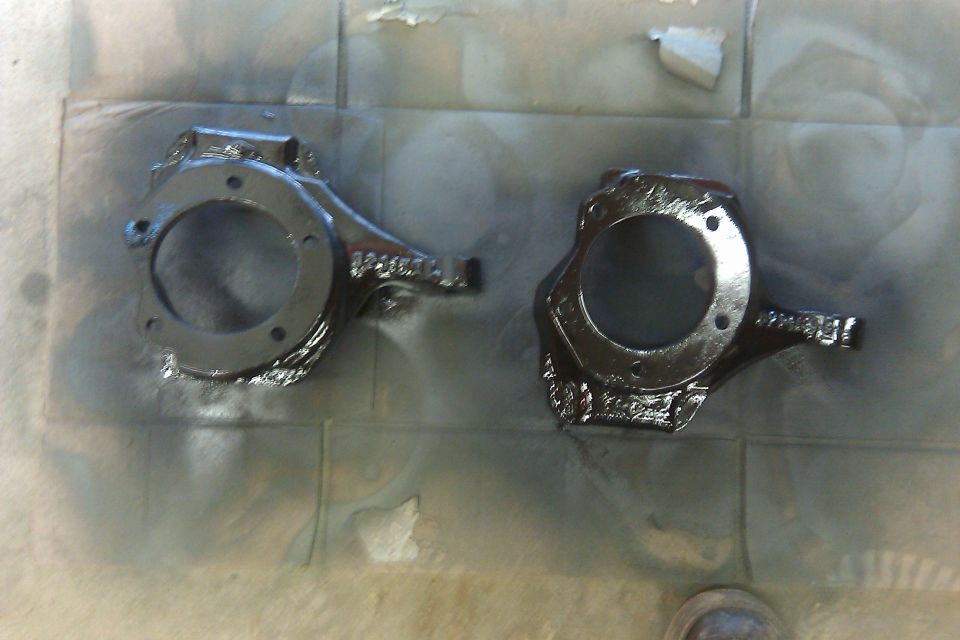 Two painted steering knuckles on a tiled surface