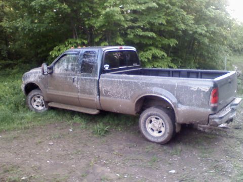 1993 Ford F-150 - This muddy pickup truck, likely from the early 2000s, displays prominent 4x4 badging on its rear fender.