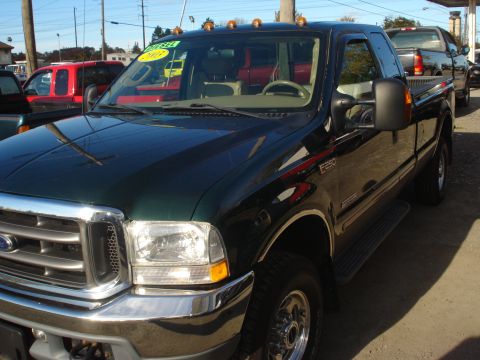 1993 Ford F-150 - This dark green Ford F-250 pickup truck is shown from a 3/4 front angle, with a 'For Sale' sign visible on the windshield.