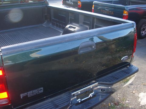 1993 Ford F-150 - Dark green Ford F-250 Super Duty pickup truck bed with a Toyota truck in the background.