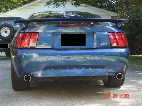 1999 Ford Mustang - This blue Ford Mustang GT is shown from the rear, parked next to a truck.