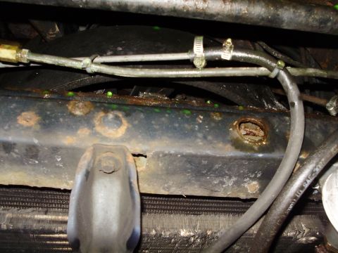 1995 Ford Bronco - Radiator support showing rust and a coolant leak. Hoses and clamps are also visible in the image.