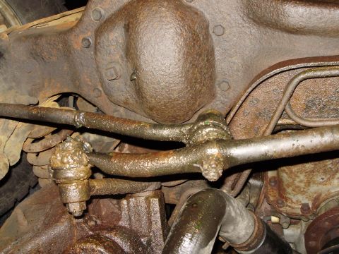 1995 Ford Bronco - Greasy steering linkage and differential housing visible on a vehicle's undercarriage.