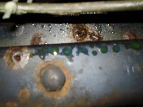 1995 Ford Bronco - Close-up of a rusted metal frame showing signs of corrosion and dripping green fluid, with a Supermotors.net watermark visible.