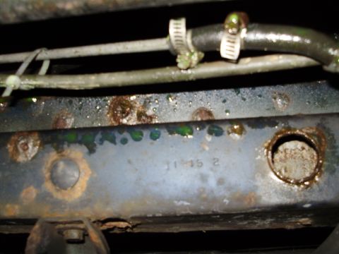 1995 Ford Bronco - Undercarriage view showing hoses and a rusty frame with stamped numbers.