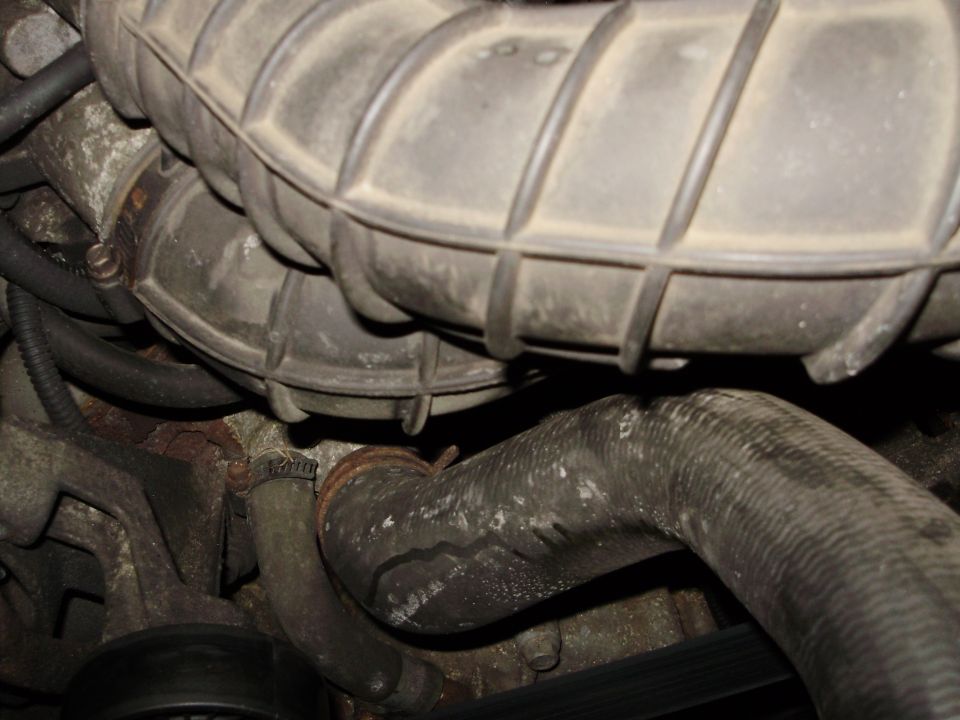 Engine bay with rubber hoses and air intake tubing, some showing wear and dirt