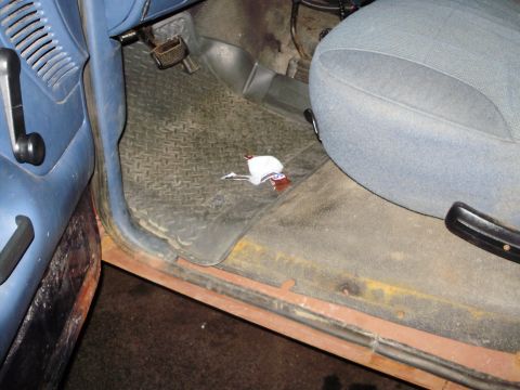 1995 Ford Bronco - The interior driver's side door and floor of a 1995 Ford Bronco show signs of wear and rust.