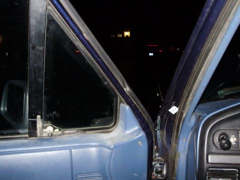 1995 Ford Bronco - The interior of a vehicle is shown at night, focusing on the door frame and window area.