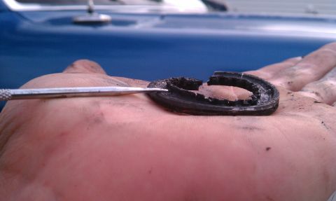 1991 Ford Bronco - A damaged rubber seal is examined on a hand, with a blue vehicle blurred in the background.