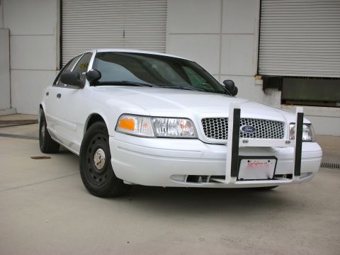 2004 Ford Crown Victoria - White Ford Crown Victoria police car parked in front of a garage door.