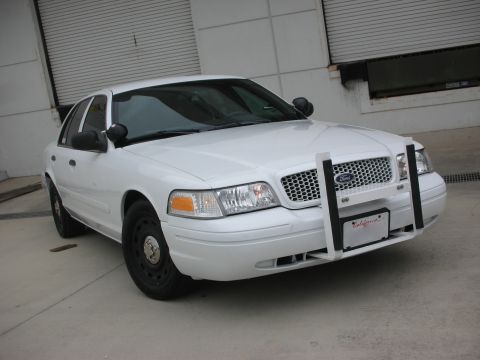 2004 Ford Crown Victoria - This white 2004 Ford Crown Victoria police car is parked in front of a garage door.