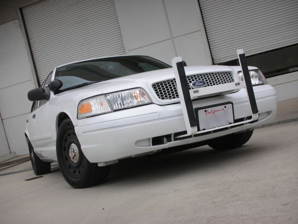 White 2004 Ford Crown Victoria with a push bar and California license plate, front view