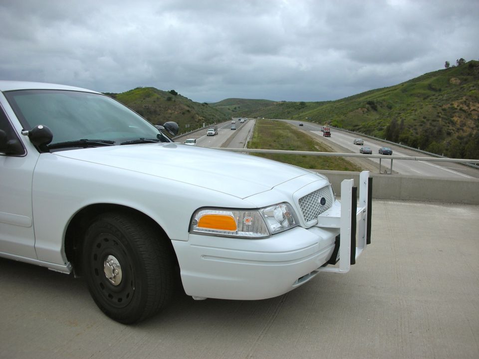 White 2004 Ford Crown Victoria police car, front quarter view, with push bumper, parked on a highway overpass