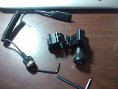 1989 Ford Bronco - A coiled cable connects to a camera flash bracket, with a hex wrench nearby on a wooden surface.