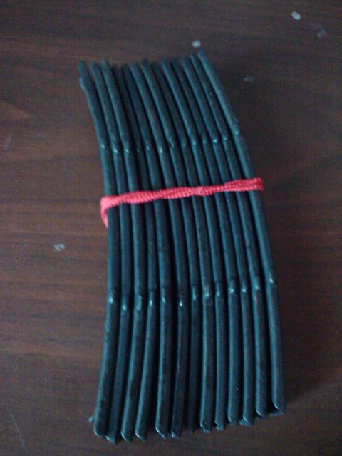 1989 Ford Bronco - A bundle of black rubber hoses, secured with red string, lies on a wooden table.