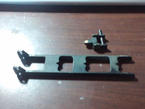 1989 Ford Bronco - A black metal automotive part, possibly a bracket or linkage, is shown with a smaller attached component.