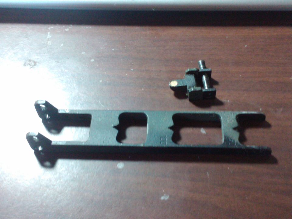 Black metal automotive part with two mounting holes and a smaller bracket