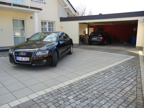 2010 Audi A4 - A black Audi sedan is parked in front of a garage, with another vehicle visible inside.