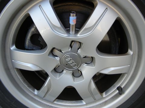 2010 Audi A4 - Close-up of a silver Audi wheel, the brand's logo and a valve stem cap decorated with the American flag and the word 'VOTE'.
