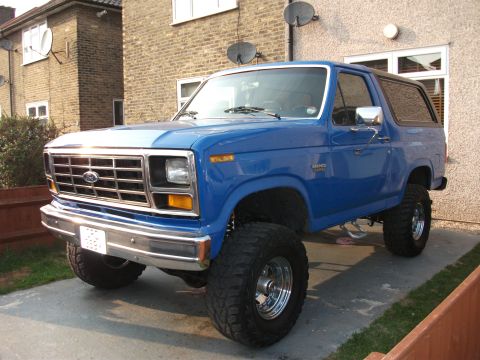 1982 Ford Bronco - Blue Ford Bronco lifted with large tires parked in driveway.