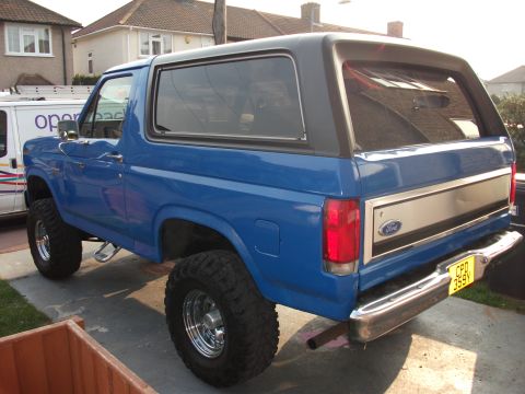 1982 Ford Bronco - This blue Ford Bronco is shown from the rear-three-quarter view, parked on a paved surface.