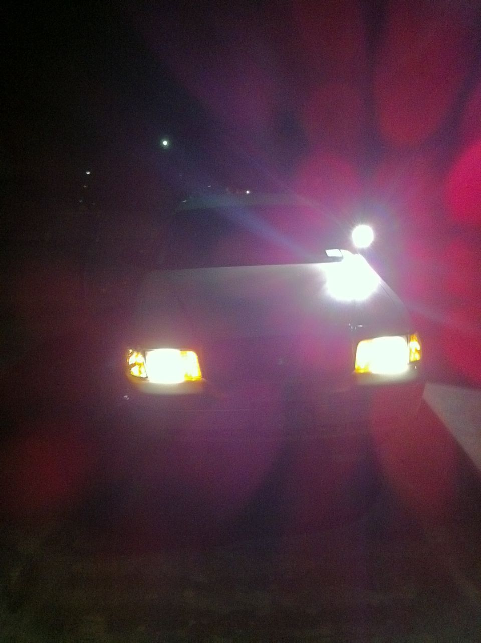 Car headlights on at night. Supermotors.net logo visible