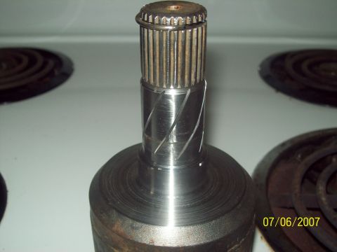 1995 Ford Probe - A close-up view of a driveshaft component, possibly for a transmission, showing its splined end and machined grooves.