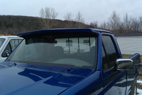 1993 Ford F-150 - A blue pickup truck is parked next to a white truck, with a visor installed above the windshield.