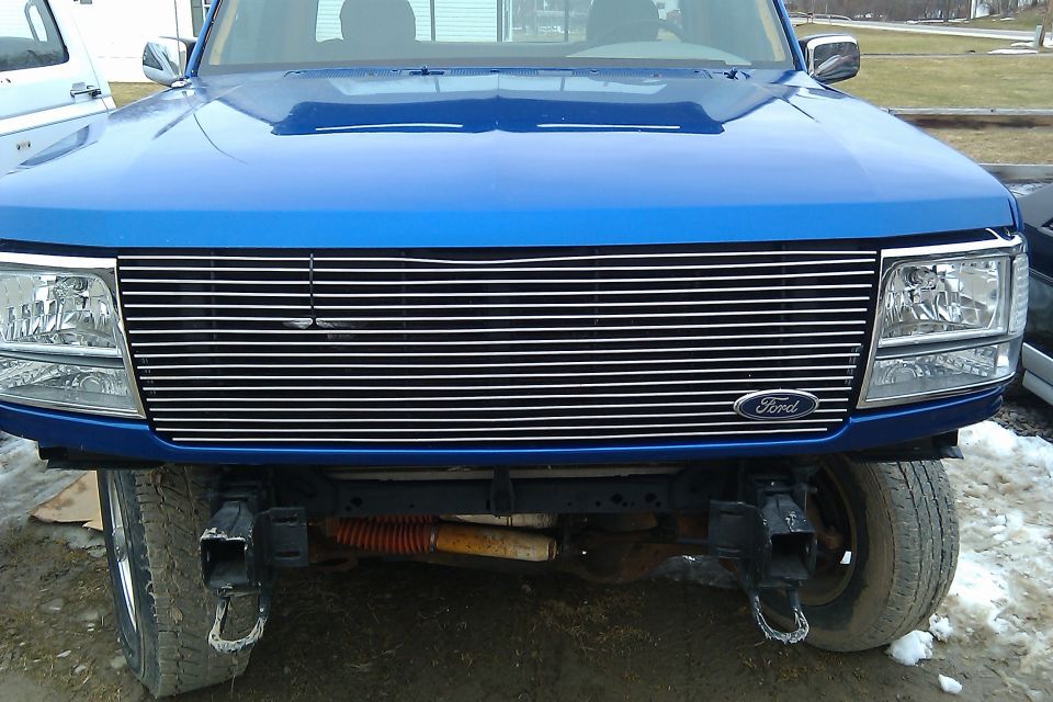 Front view of a blue 1992 Ford F-150 with a chrome grille and aftermarket tow hooks