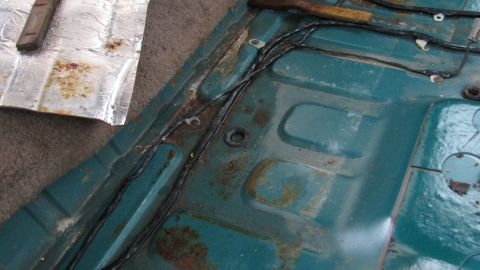1992 Ford Bronco - The floor pan of a vehicle shows significant rust and exposed wiring, indicating wear and tear.