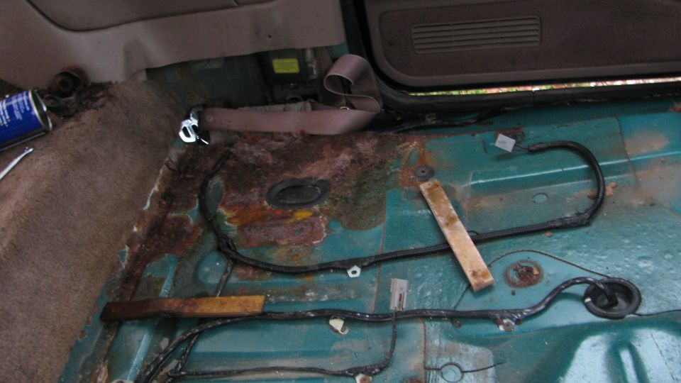 Vehicle interior floor with extensive rust and exposed wiring