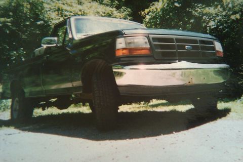 1993 Ford F-150 - A dark green Ford F-Series truck is parked outdoors with trees in the background.