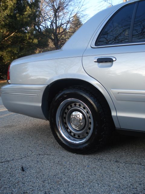 2000 Ford Crown Victoria - The rear passenger side of a silver sedan is shown, focusing on the wheel and fender area.