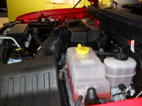 2011 Ford F-150 - Close-up view of a red vehicle's engine bay, showing various fluid reservoirs and engine components.