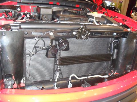 2011 Ford F-150 - The front of a red 2011 Ford F-150 is shown, focusing on the radiator and horn assembly.