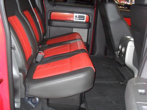 2011 Ford F-150 - The interior of a truck shows red and black seats with black floor mats and red door trim.