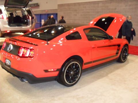 2012 Ford Mustang - A red 2012 Ford Mustang Boss 302 is displayed with its hood open, parked next to another vehicle.
