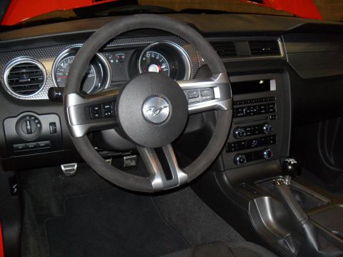 2012 Ford Mustang - The interior of a Ford Mustang features a leather-wrapped steering wheel and a modern dashboard layout.
