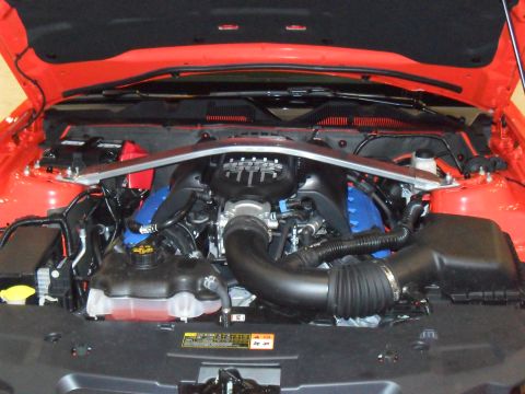 2012 Ford Mustang - The engine bay of an orange Ford Mustang shows its V8 engine with blue accents.