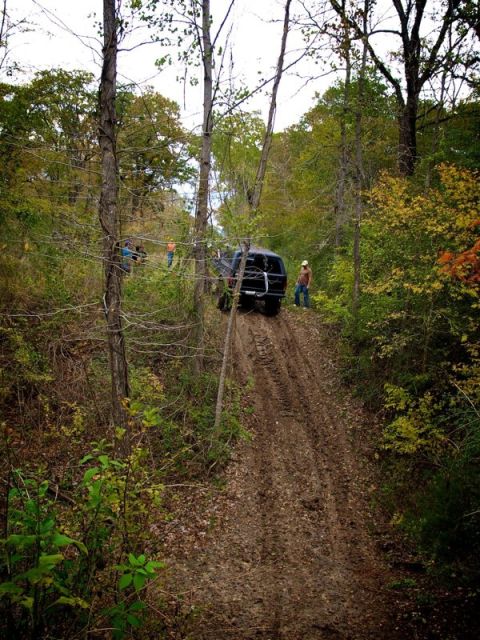 1995 Ford Bronco - 1995 Ford Bronco navigating a challenging muddy trail in a wooded area.