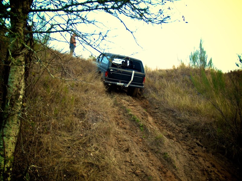 Black 1995 Ford Bronco driving up a muddy hill