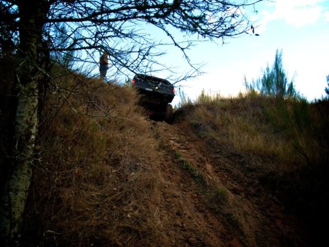 1995 Ford Bronco - Vehicle navigates a challenging off-road climb on a dirt hill under a bright sky.