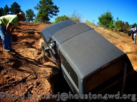 1995 Ford Bronco - A dark 1995 Ford Bronco is seen off-roading on a steep, rutted dirt path with a person observing.