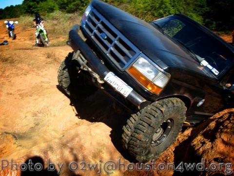 1995 Ford Bronco - Ford Bronco tackling rough terrain, with dirt bikes visible on the trail.