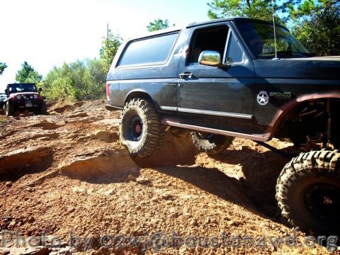 1995 Ford Bronco - Bronco tackling an off-road trail with a Jeep following behind.