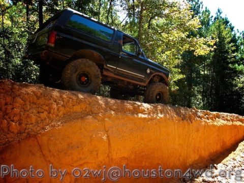 1995 Ford Bronco - This black Ford Bronco is navigating a challenging off-road trail.