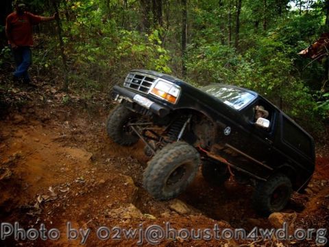1995 Ford Bronco - A black 1995 Ford Bronco navigates a challenging off-road trail, demonstrating its capabilities.
