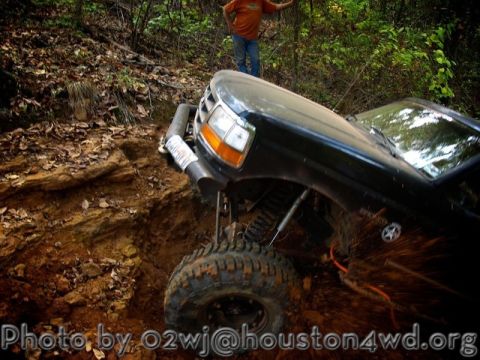 1995 Ford Bronco - This vehicle is navigating a challenging off-road trail with steep inclines and loose dirt.