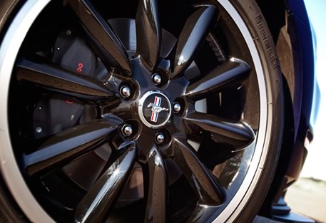 2012 Ford Mustang - Close-up of a black Ford Mustang wheel, red brake calipers and the iconic Mustang emblem.